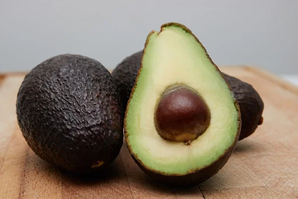 Tres aguacates de la variedad Fuerte, uno de ellos abierto por la mitad.